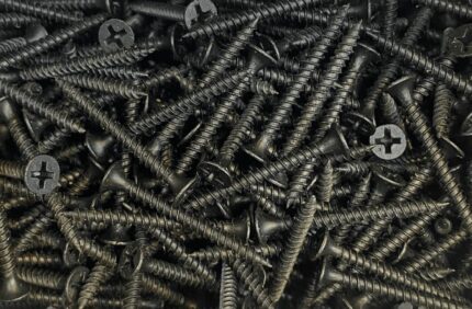 A top-down, close-up view of a large pile of black gypsum screws with Phillips heads, scattered randomly.