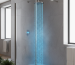 A modern bathroom with a walk-in shower. Blue, cold water streams from the showerhead onto the shower floor